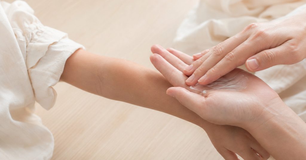 異位性皮膚炎居家照護示意圖：為孩子的手臂塗抹保濕乳霜